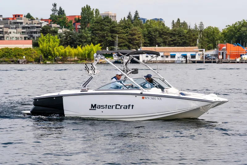 Slide: The Image of 2008 MasterCraft MariStar 235 SS boat cruising on a lake near a cityscape. - 0
