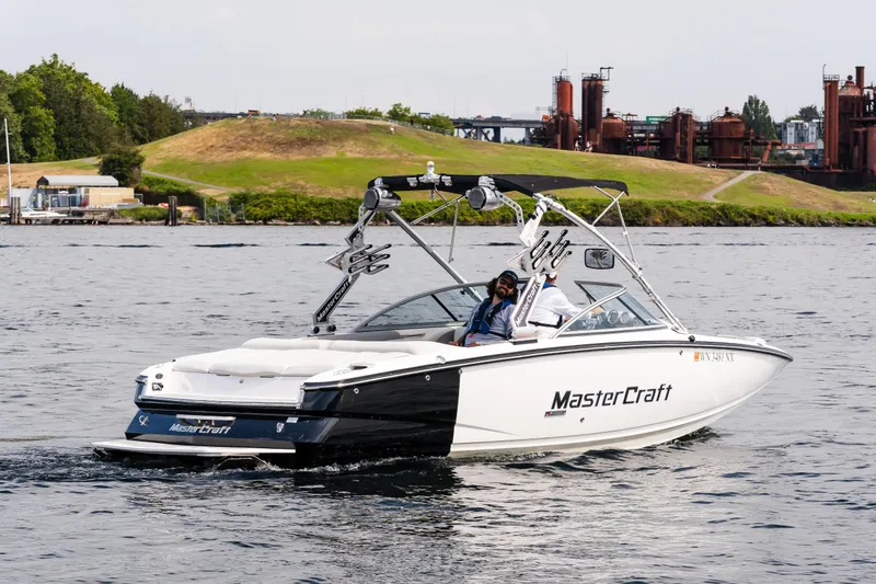 Slide: The Image of 2008 MasterCraft MariStar 235 SS boat cruising on a scenic lake with industrial backdrop. - 1