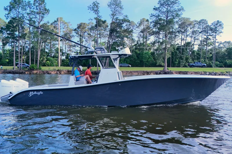 Slide: The Image of 2022 Yellowfin 34 Offshore boat cruising on a calm river with trees in the background. - 2
