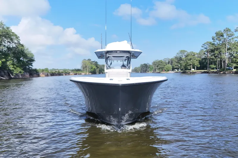 Slide: The Image of 2022 Yellowfin 34 Offshore boat cruising on a scenic river under a clear blue sky. - 3