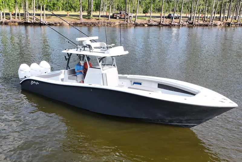 Slide: The Image of 2022 Yellowfin 34 Offshore boat on calm water, surrounded by trees. - 7