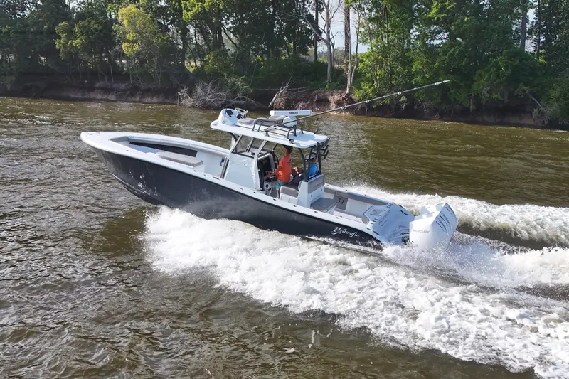 Slide: The Image of 2022 Yellowfin 34 Offshore boat cruising on a river with lush green trees. - 8
