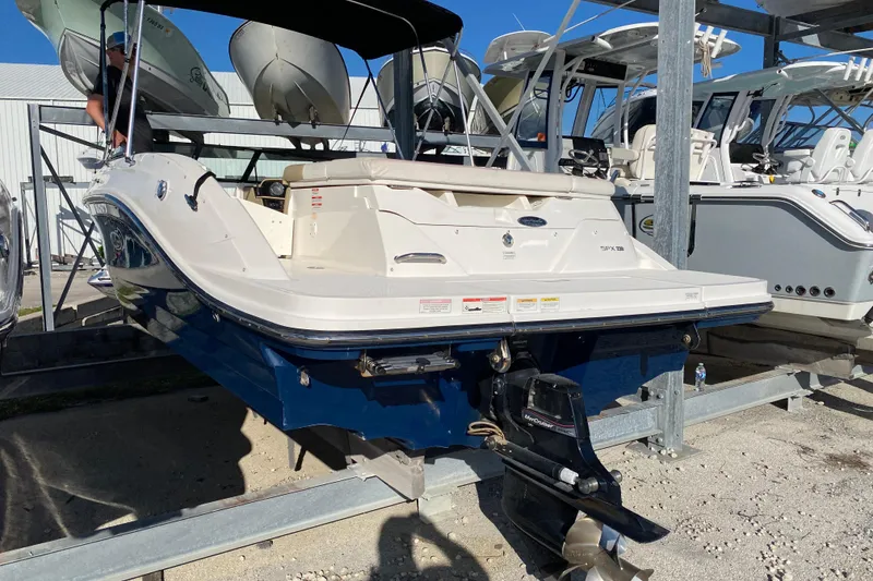 Slide: The Image of 2018 Sea Ray SPX 230 boat with blue hull on a storage rack under a clear sky. - 2