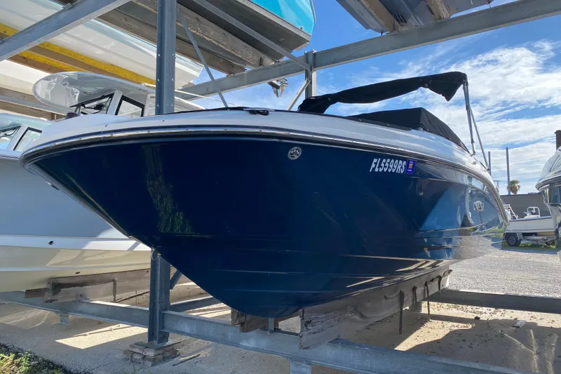 Slide: The Image of 2018 Sea Ray SPX 230 boat in storage, blue hull, covered, sunny day. - 28