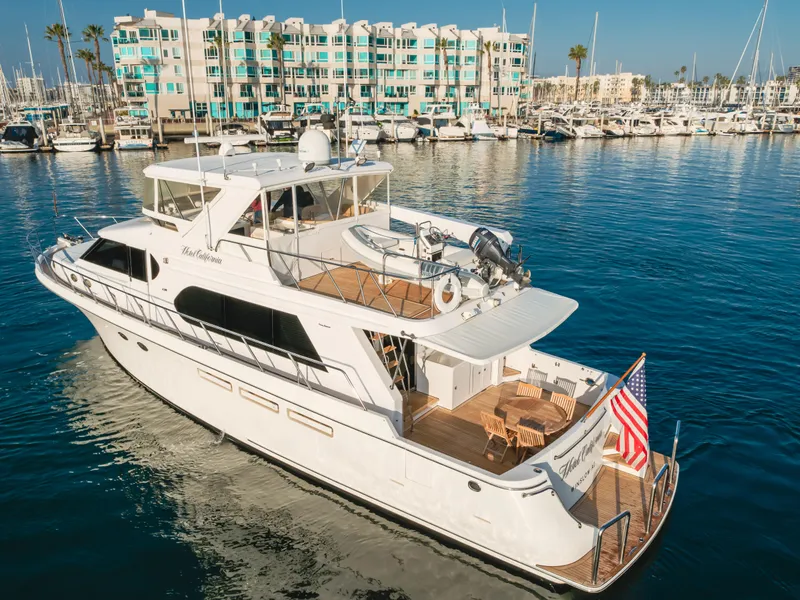 Slide: The Image of 2003 Ocean Alexander 64 Pilothouse yacht docked in a marina, with waterfront buildings in the background. - 2
