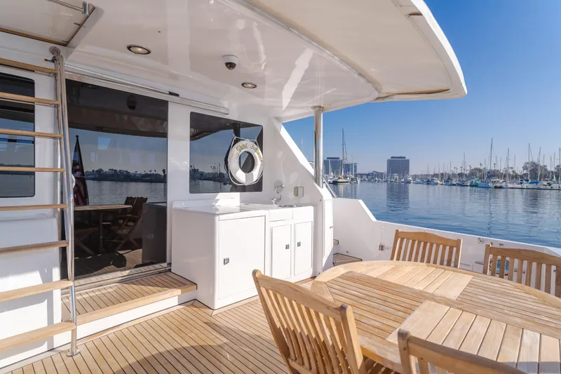 Slide: The Image of 2003 Ocean Alexander 64 Pilothouse yacht deck with wooden furniture and marina view. - 49