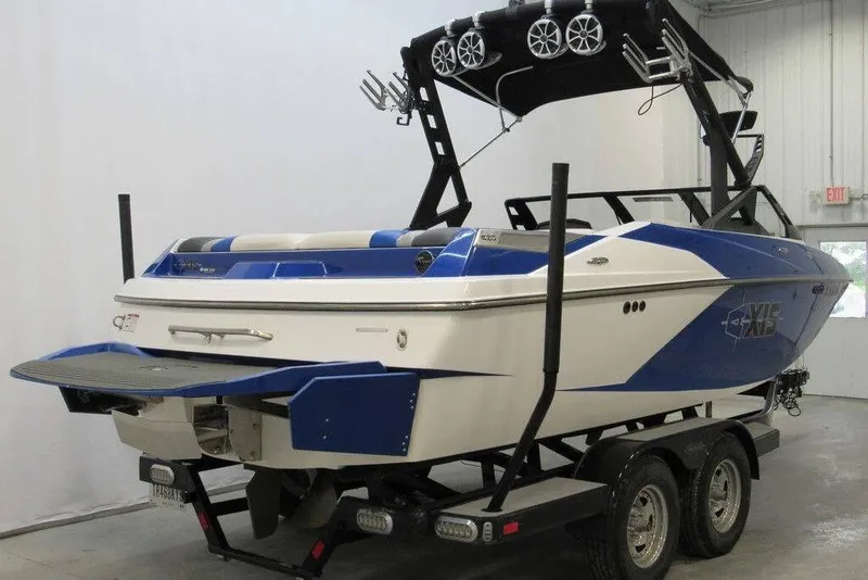 Slide: The Image of 2016 Axis A20 boat on trailer, blue and white design, in indoor setting. - 2
