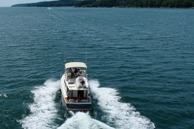 Slide: The Image of 1990 Nauset Flybridge Cruiser with extended hardtop navigating open waters. - 1