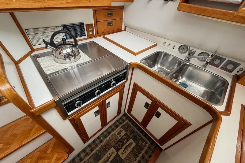 Slide: The Image of Compact kitchen in 1990 Nauset Flybridge Cruiser, featuring stove, sink, and wooden cabinetry. - 14