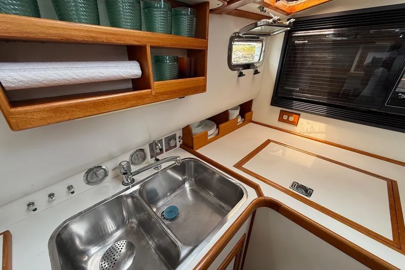 Slide: The Image of 1990 Nauset Flybridge Cruiser kitchen with stainless steel sink, wooden shelves, and microwave. - 16