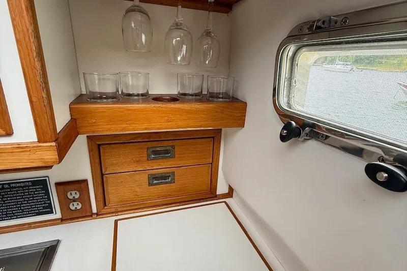 Slide: The Image of 1990 Nauset Flybridge Cruiser interior with wooden cabinetry and glassware storage. - 17