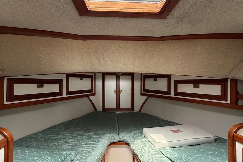 Slide: The Image of 1990 Nauset Flybridge Cruiser cabin interior with teal bedding and wooden accents. - 20