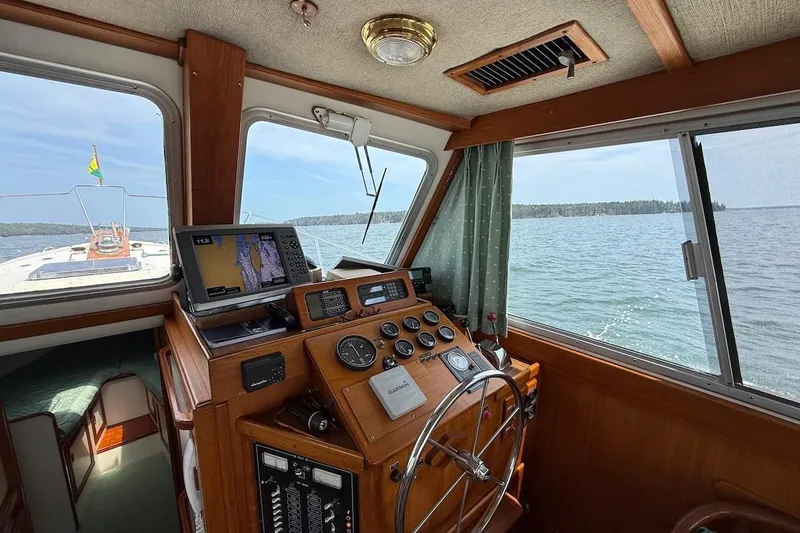 Slide: The Image of 1990 Nauset Flybridge Cruiser helm with navigation equipment, overlooking serene waters. - 27