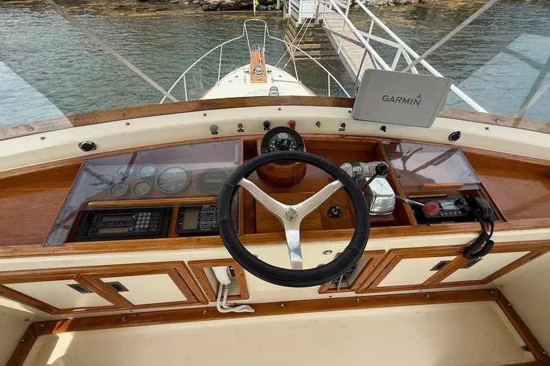Slide: The Image of 1990 Nauset Flybridge Cruiser helm with Garmin navigation, wooden dashboard, and steering wheel. - 31