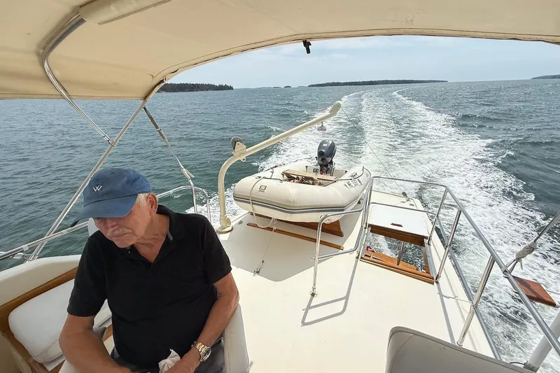 Slide: The Image of Man relaxing on 1990 Nauset Flybridge Cruiser with extended hardtop, ocean view in background. - 38