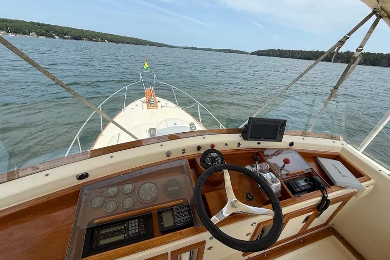 Slide: The Image of 1990 Nauset Flybridge Cruiser helm with extended hardtop, featuring navigation instruments and scenic water view. - 48