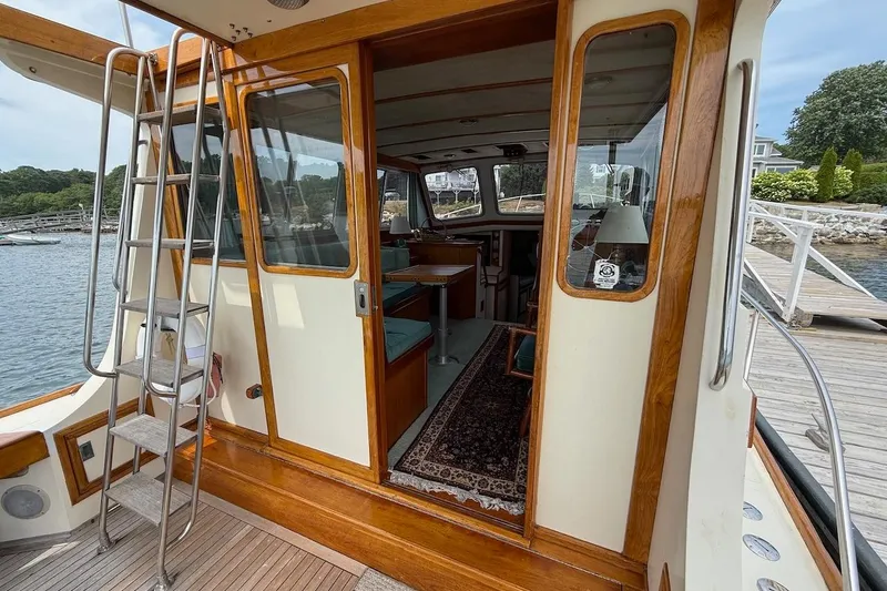 Slide: The Image of 1990 Nauset Flybridge Cruiser with extended hardtop, featuring a wooden interior and dockside view. - 5