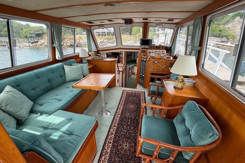 Slide: The Image of Luxurious 1990 Nauset Flybridge Cruiser interior with teal seating, wooden accents, and scenic water views. - 6