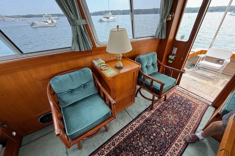 Slide: The Image of Interior of 1990 Nauset Flybridge Cruiser with teal chairs, wooden decor, and ocean view. - 7