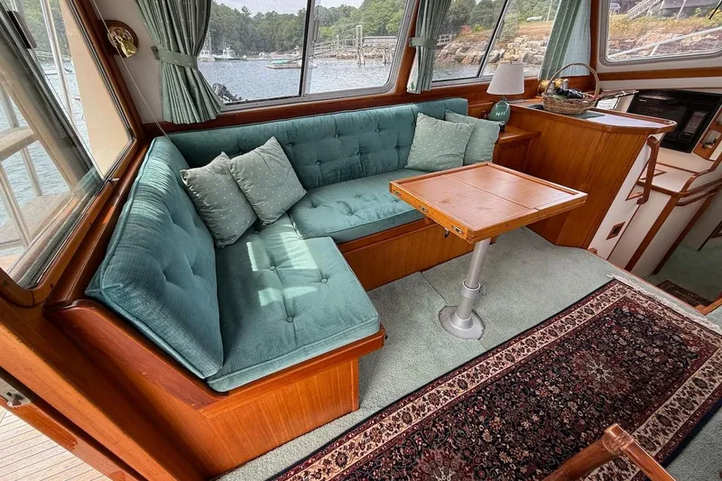 Slide: The Image of Cozy interior of 1990 Nauset Flybridge Cruiser with teal seating and wooden accents. - 8
