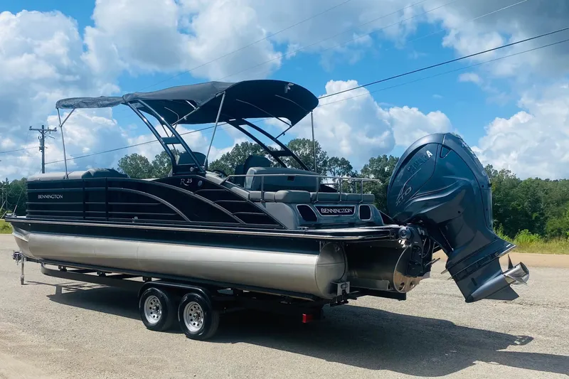 Slide: The Image of 2023 Bennington 25RSBA pontoon boat on trailer, featuring sleek design and powerful outboard motor. - 12