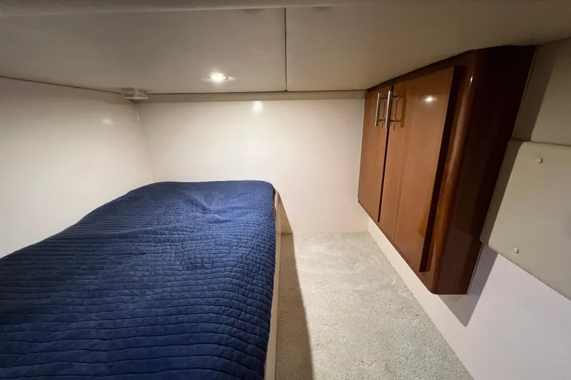 Slide: The Image of 2004 Carver 466 Motor Yacht cabin with blue bedding and wooden cabinets. - 36