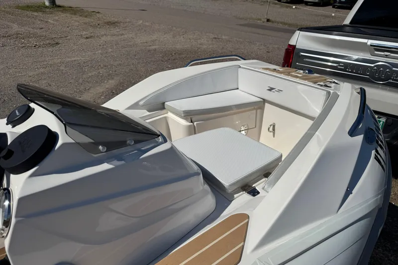 Slide: The Image of 2022 Zar Tender ZF0 boat interior with seating and dashboard, parked beside a vehicle. - 14