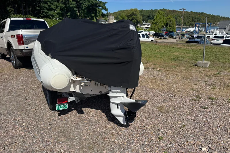 Slide: The Image of 2022 Zar Tender ZF0 boat covered, parked on gravel near a white truck. - 2