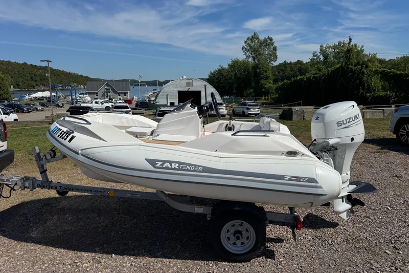 Slide: The Image of 2022 Zar Tender ZF0 boat on trailer with Suzuki outboard motor, parked near marina. - 5