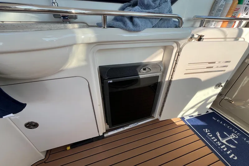 Slide: The Image of Interior of 2006 Sea Ray 380 Sundancer with mini fridge and open cabinet. - 28