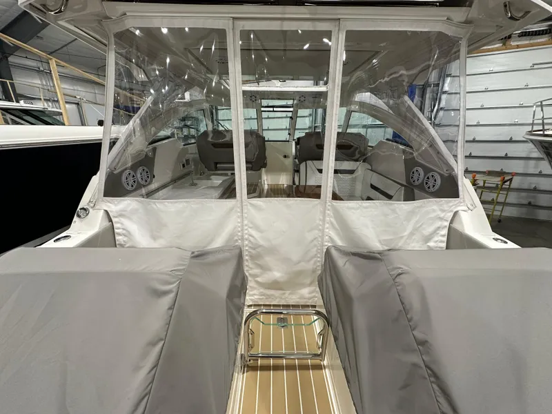 Slide: The Image of 2024 Tiara Yachts 34 LX interior with covered seating and clear enclosure in a showroom. - 13