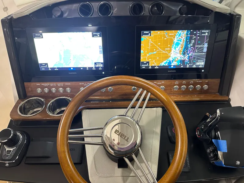 Slide: The Image of 2024 Tiara Yachts 34 LX dashboard with dual Garmin displays and wooden steering wheel. - 21