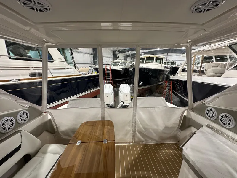 Slide: The Image of 2024 Tiara Yachts 34 LX interior with seating, table, and view of docked boats. - 6