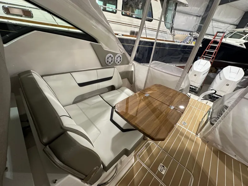 Slide: The Image of 2024 Tiara Yachts 34 LX interior with seating and wooden table in a boat showroom. - 9