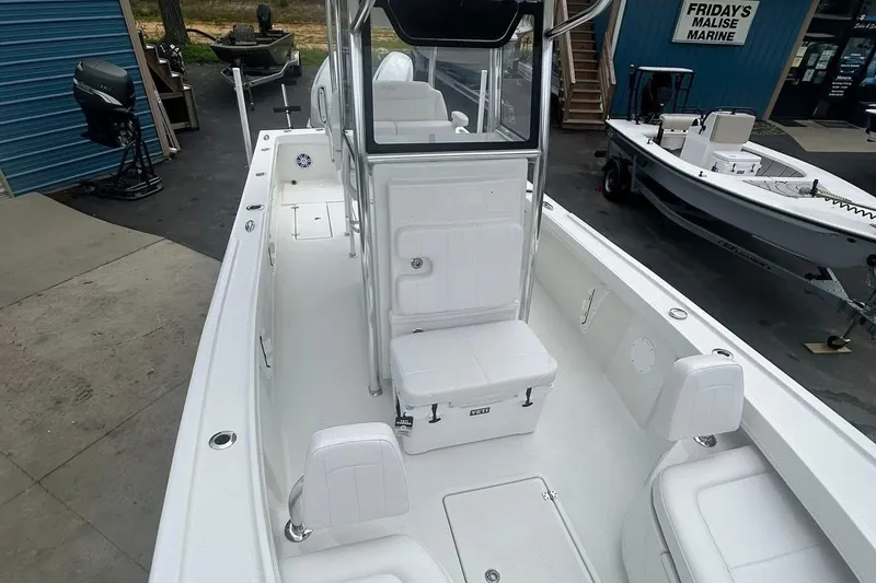 Slide: The Image of 2026 Pair Customs 24 Center Console DV boat with sleek white interior at marine dealership. - 1