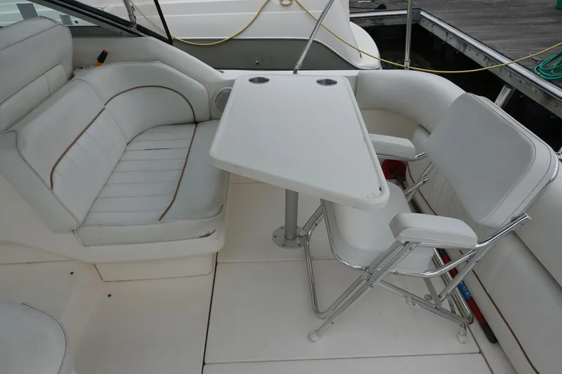 Slide: The Image of 1997 Sea Ray 270 Sundancer boat interior with white seating and table setup. - 8