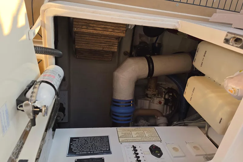 Slide: The Image of Engine compartment of a 2003 Riviera 48 Flybridge yacht, featuring pipes and control panels. - 12