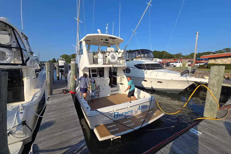 Slide: The Image of 2003 Riviera 48 Flybridge yacht docked at marina with people boarding. - 2