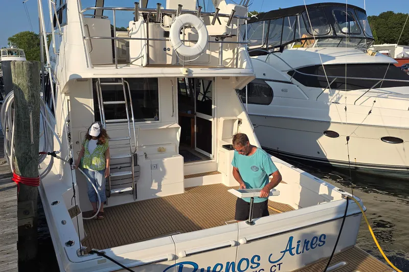 Slide: The Image of 2003 Riviera 48 Flybridge yacht docked, with two people on deck, sunny day. - 3