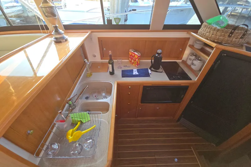 Slide: The Image of 2003 Riviera 48 Flybridge yacht kitchen with wooden cabinetry, sink, and appliances. - 38