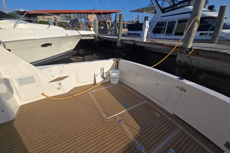 Slide: The Image of 2003 Riviera 48 Flybridge yacht docked, featuring a spacious teak deck and marina backdrop. - 4