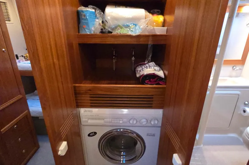 Slide: The Image of Laundry area in 2003 Riviera 48 Flybridge yacht with wooden cabinetry and washing machine. - 59