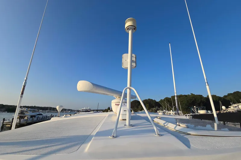 Slide: The Image of 2003 Riviera 48 Flybridge yacht with radar equipment, docked under clear blue sky. - 63
