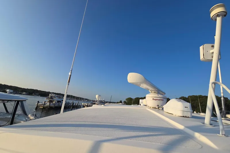 Slide: The Image of 2003 Riviera 48 Flybridge yacht with radar equipment, docked under clear blue sky. - 64