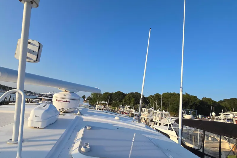 Slide: The Image of 2003 Riviera 48 Flybridge yacht docked at marina under clear blue sky. - 65