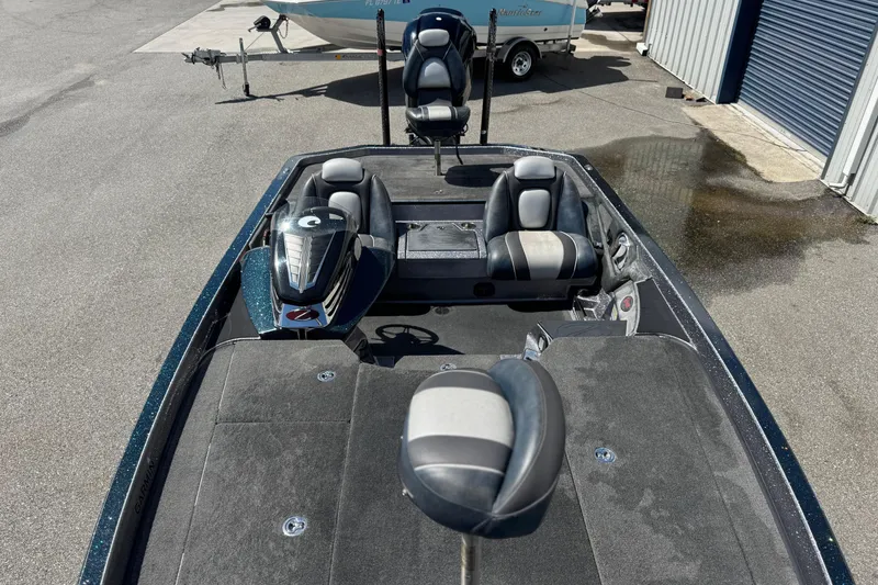 Slide: The Image of 2014 Ranger 520C boat with seating and motor, parked near a trailer and building. - 8