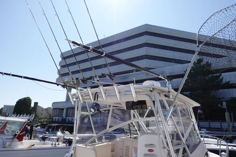 Slide: The Image of 2002 Grady White 300 Marlin boat with fishing rods, docked near a modern building. - 5