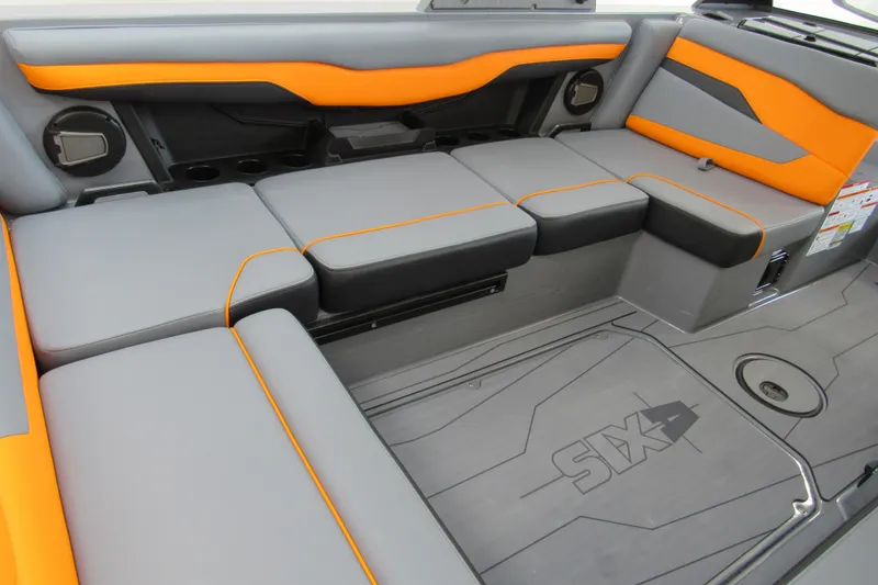 Slide: The Image of 2025 Axis T220 boat interior with gray and orange seating, featuring cup holders and storage compartments. - 6