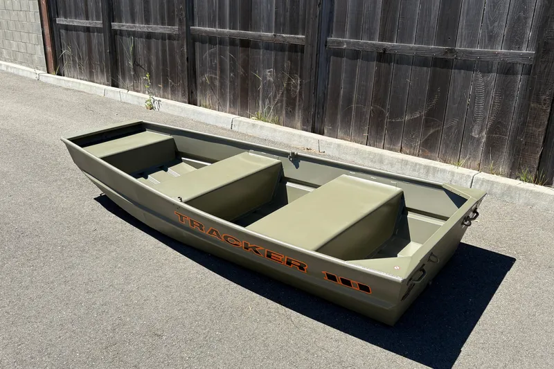 Slide: The Image of 2026 Tracker Grizzly 10 Jon boat in olive green, parked on pavement. - 1