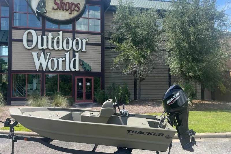 Slide: The Image of 2026 Tracker Grizzly 1648 SC boat outside Outdoor World store. - 3